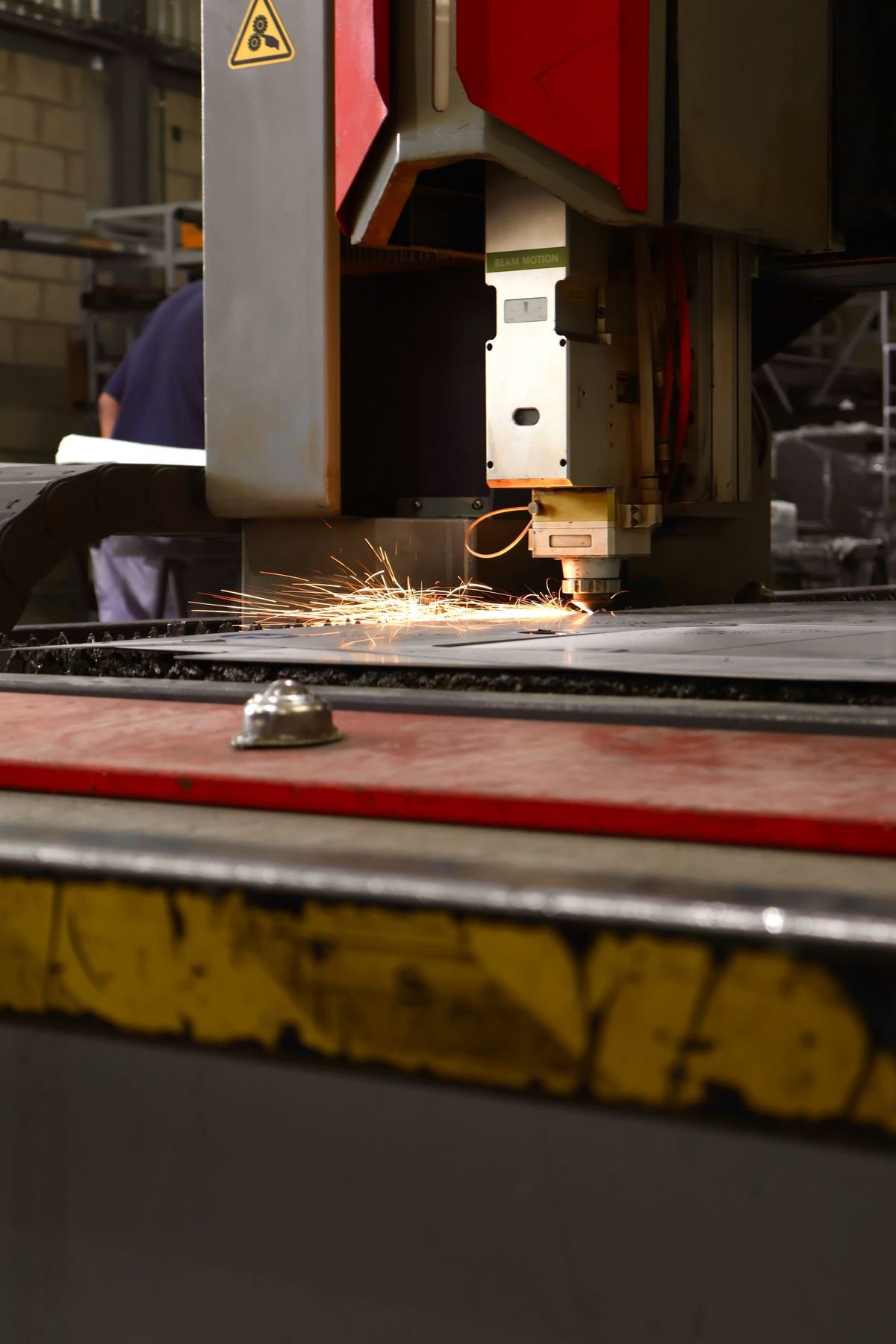Cabezal de corte láser CNC cortando una placa de acero, chispas al corte