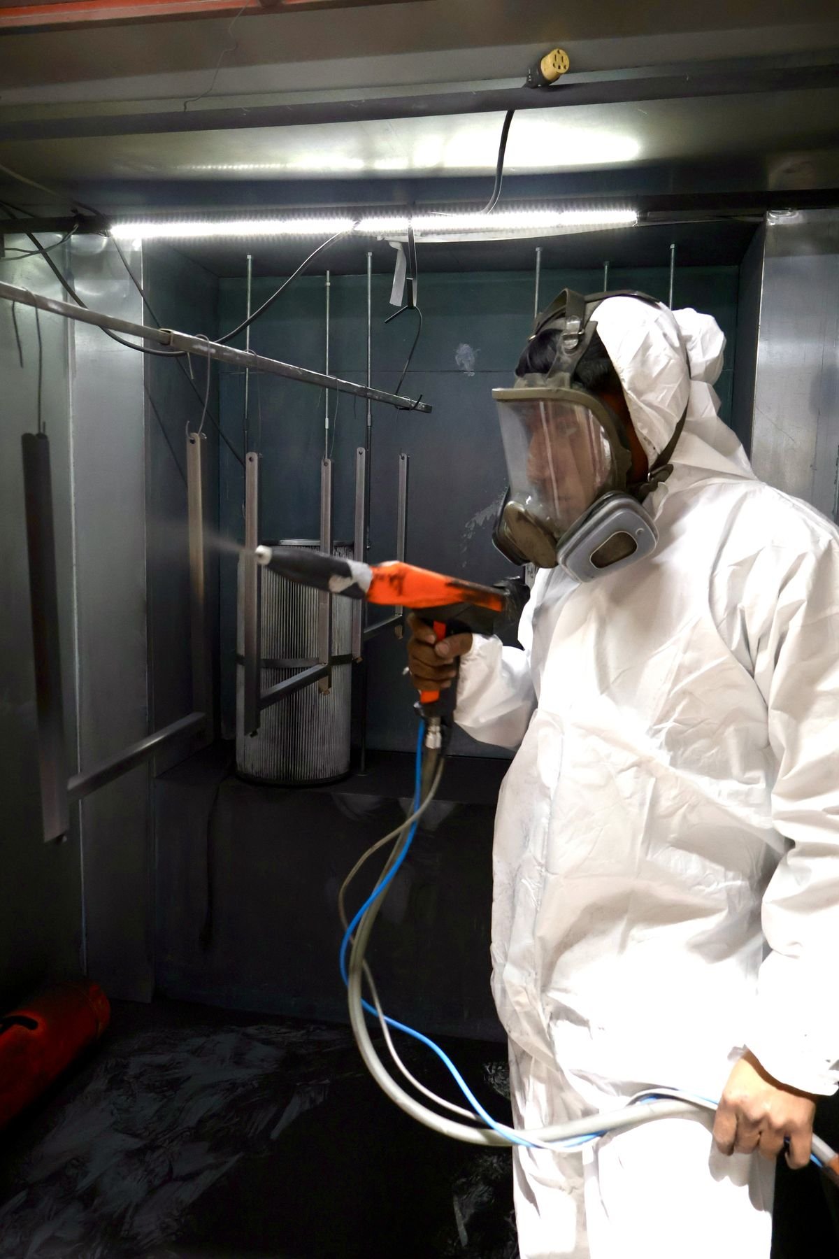 Técnico de Rolacero Multiprocesos con equipo de protección aplicando pintura electrostática en cabina