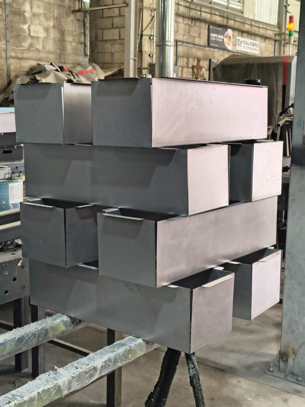 Cajas metálicas apiladas junto a máquina de corte láser