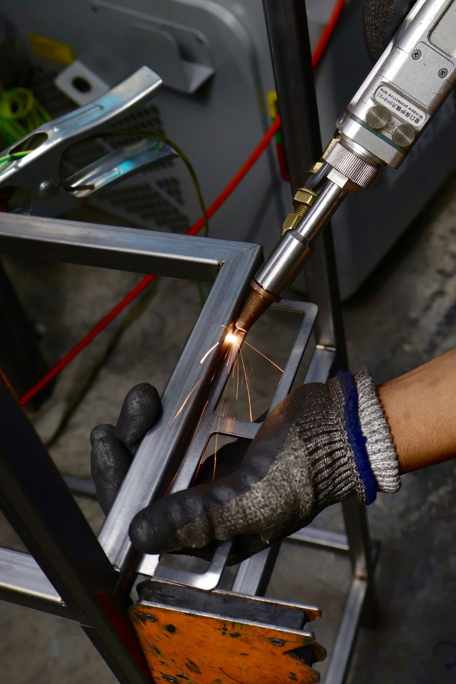 Soldador de Rolacero Multiprocesos con guante y chispas sobre estructura metálica